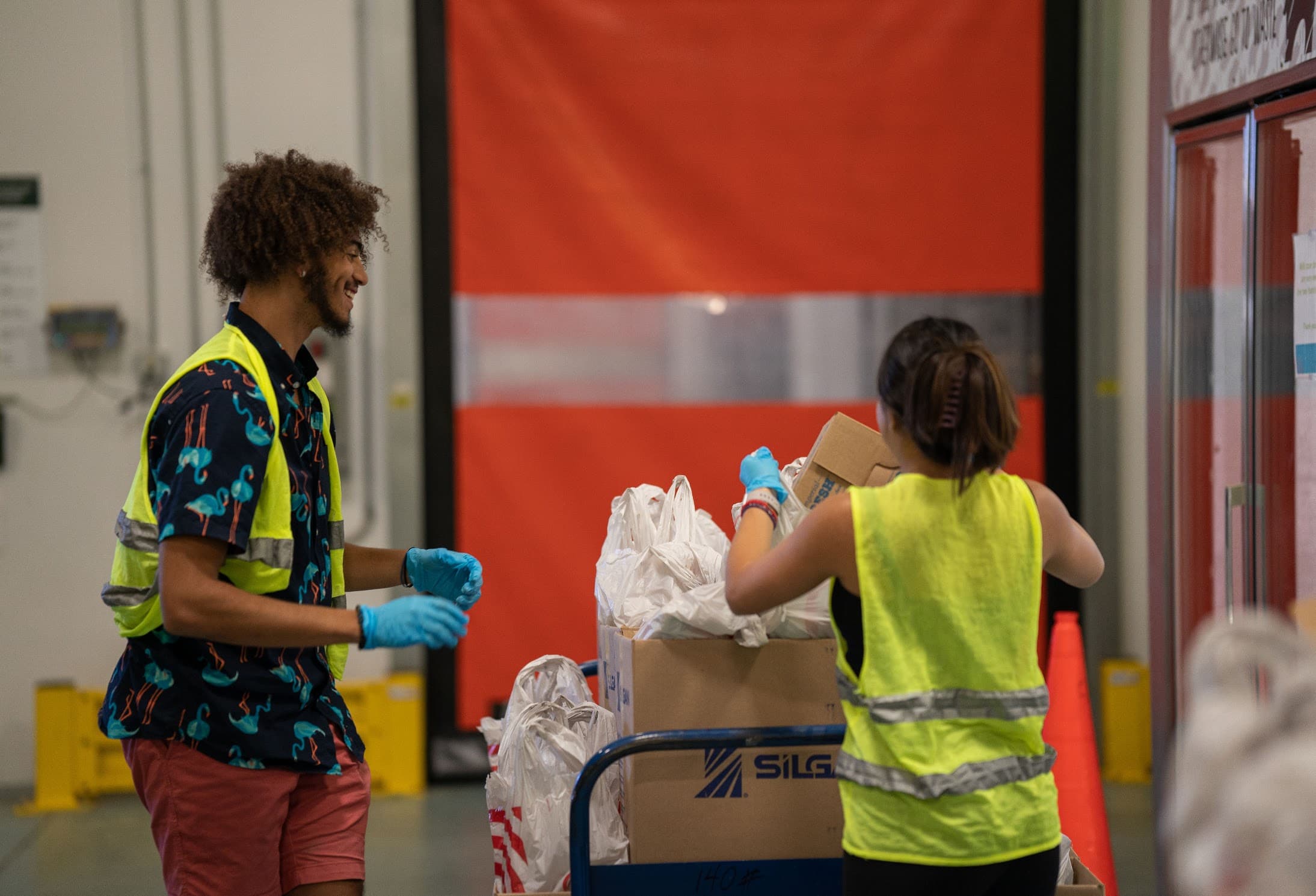 Volunteers in safety vests sorting donated food at a warehouse